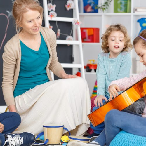 Little girl playing the guitar during music classes in kindergarten