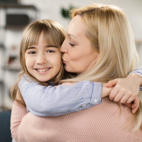 Happy loving single mom hugging cute little adopted kid daughter laughing bonding
